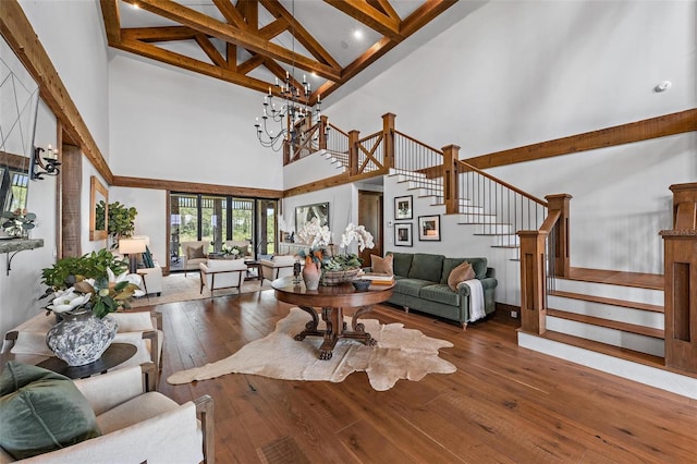 living area with wood-type flooring, stairs, beam ceiling, high vaulted ceiling, and a notable chandelier