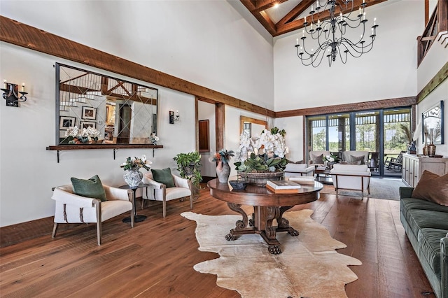 living area featuring beam ceiling, a high ceiling, hardwood / wood-style flooring, and a notable chandelier