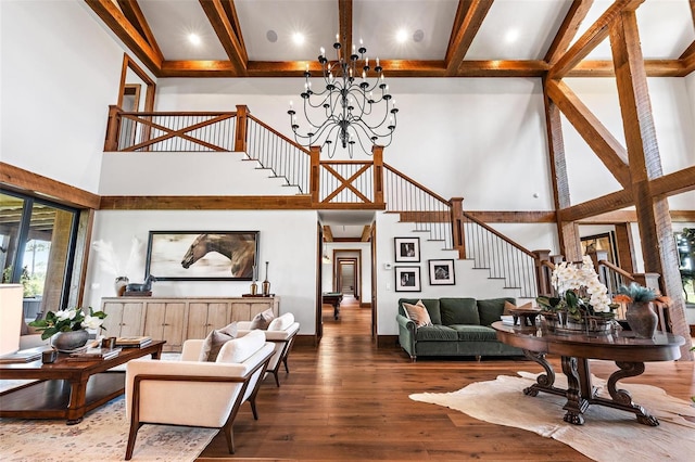 living room featuring a towering ceiling, hardwood / wood-style flooring, stairway, beam ceiling, and a notable chandelier