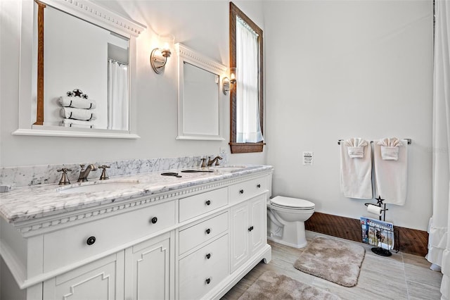 bathroom featuring a sink, toilet, and double vanity