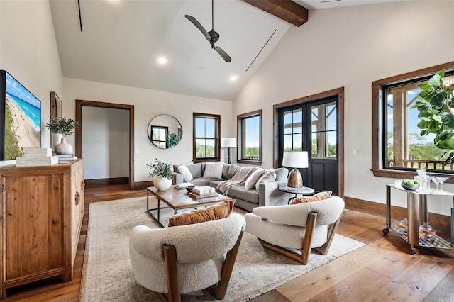 living area featuring high vaulted ceiling, beamed ceiling, a ceiling fan, and light wood-style floors