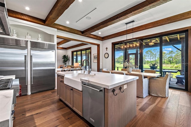 kitchen featuring dark wood-style floors, high end appliances, a sink, and a kitchen island with sink