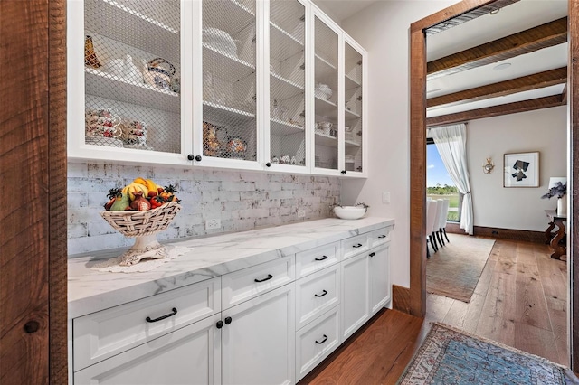 bar featuring hardwood / wood-style flooring, visible vents, baseboards, backsplash, and beam ceiling