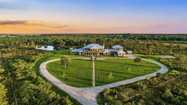 aerial view at dusk with a water view and a wooded view