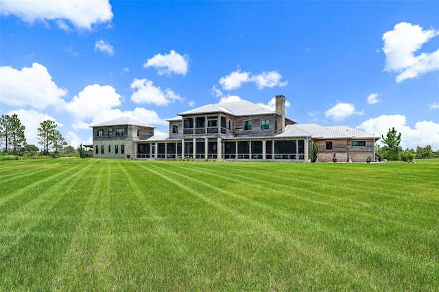 rear view of property with a lawn, a chimney, and a sunroom