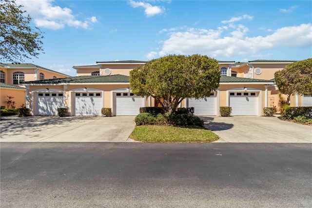 view of front of house featuring a tile roof, a garage, and stucco siding