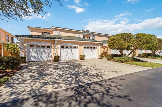 view of front of house with a tiled roof, a garage, driveway, and stucco siding