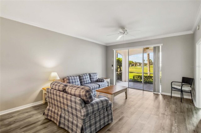 living area with a ceiling fan, wood finished floors, baseboards, and ornamental molding