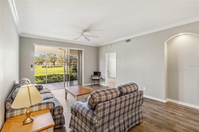 living room featuring visible vents, ornamental molding, a ceiling fan, wood finished floors, and baseboards