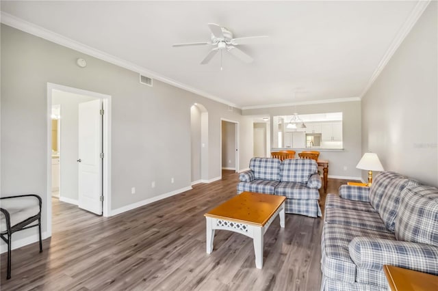 living room with visible vents, baseboards, ornamental molding, wood finished floors, and arched walkways