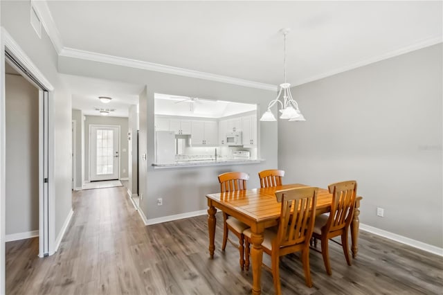 dining room featuring ceiling fan with notable chandelier, wood finished floors, baseboards, and ornamental molding