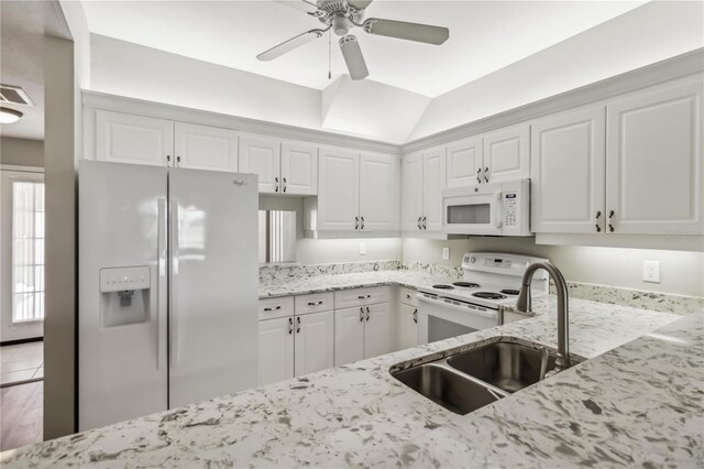 kitchen featuring light stone counters, white cabinets, white appliances, and a sink