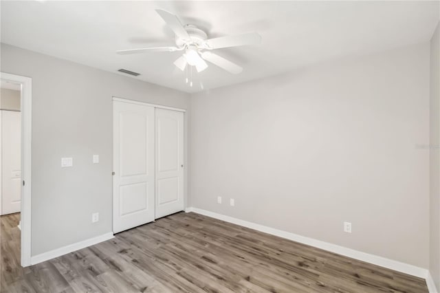 unfurnished bedroom featuring a ceiling fan, wood finished floors, visible vents, baseboards, and a closet