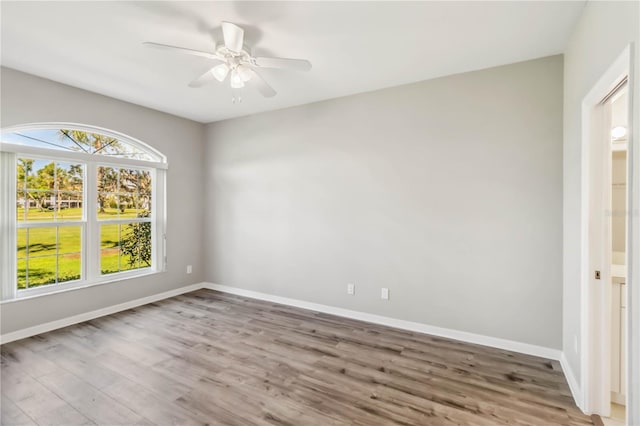 empty room with a ceiling fan, wood finished floors, and baseboards