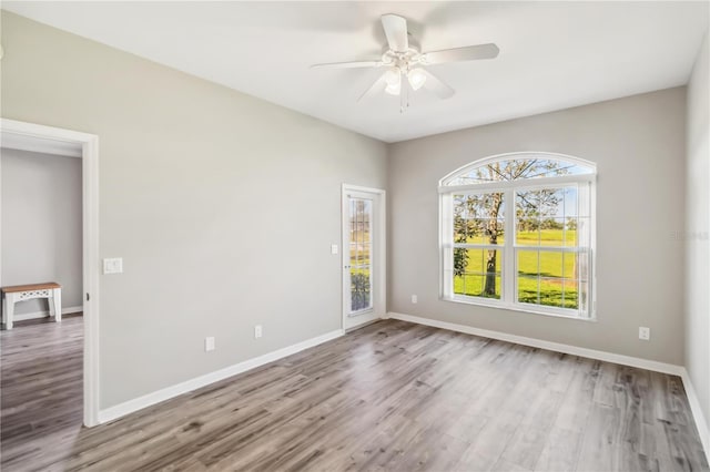 spare room with baseboards, wood finished floors, and a ceiling fan