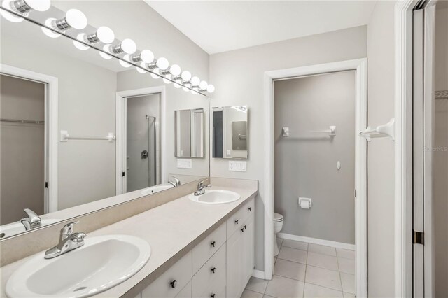 bathroom featuring tile patterned flooring, a spacious closet, toilet, and a sink