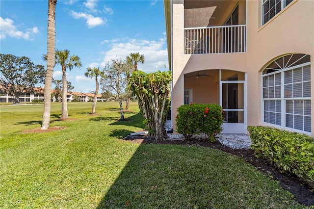 view of yard featuring a balcony and a ceiling fan