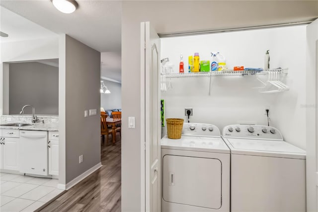 clothes washing area featuring washer and clothes dryer, laundry area, light wood-style floors, and a sink