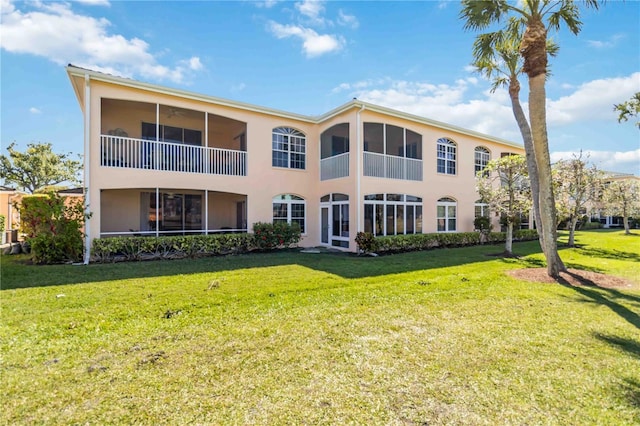 back of property featuring stucco siding and a lawn