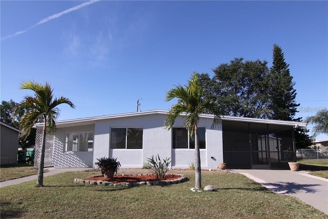 view of front of home with a carport, a front yard, a sunroom, and concrete driveway