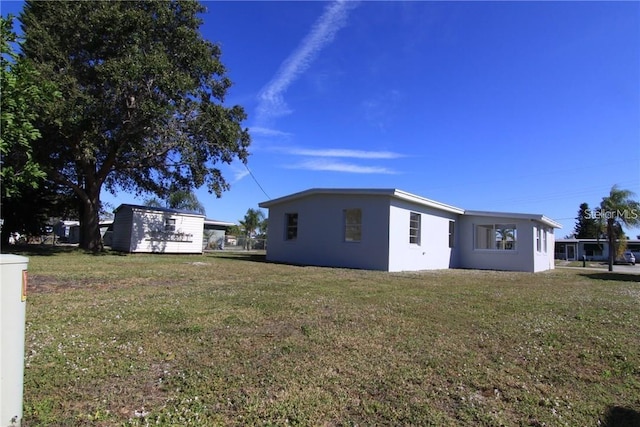 exterior space with stucco siding and a yard