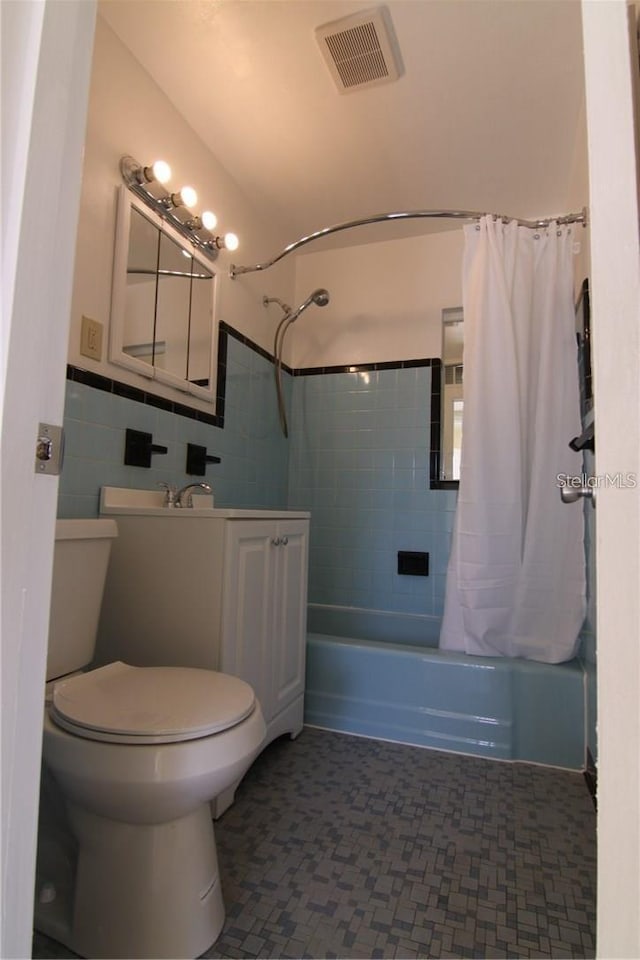 full bathroom featuring tile walls, visible vents, toilet, shower / bath combo, and vanity