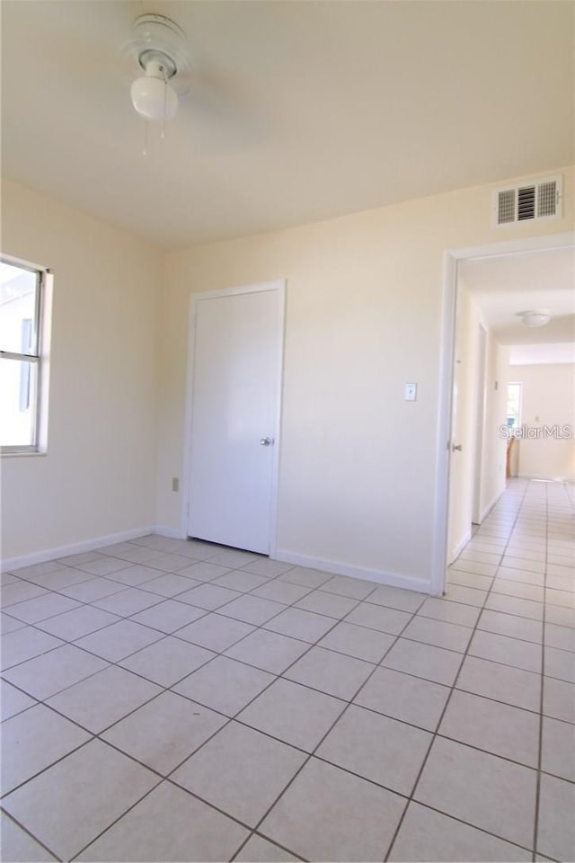 empty room with light tile patterned floors, baseboards, visible vents, and ceiling fan