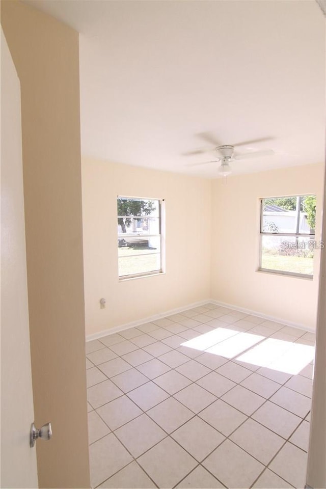 spare room with ceiling fan, baseboards, and a wealth of natural light