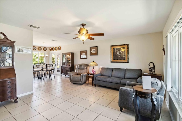 living area with light tile patterned floors, a ceiling fan, visible vents, and baseboards