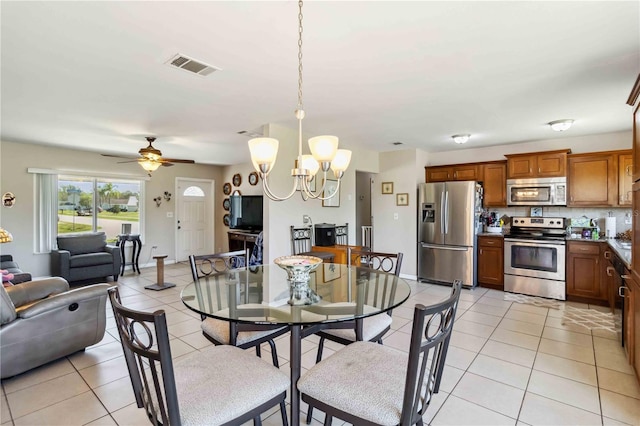 dining space with light tile patterned floors, visible vents, ceiling fan with notable chandelier, and baseboards