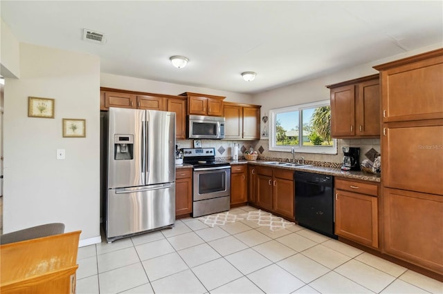 kitchen featuring brown cabinetry, visible vents, a sink, appliances with stainless steel finishes, and backsplash