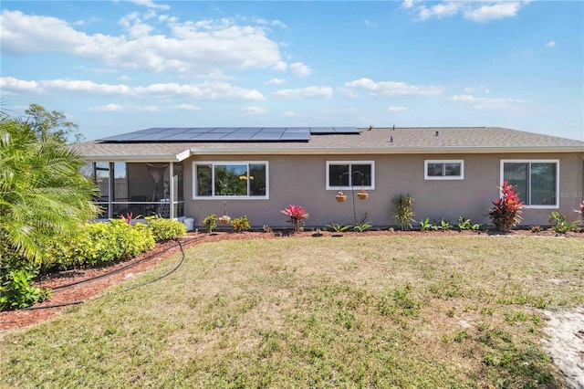 back of house with stucco siding, solar panels, a lawn, and a sunroom