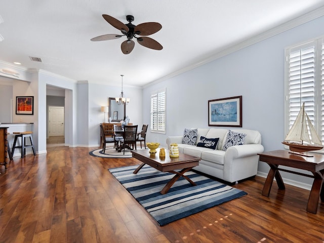 living area featuring hardwood / wood-style flooring, ceiling fan with notable chandelier, visible vents, baseboards, and crown molding