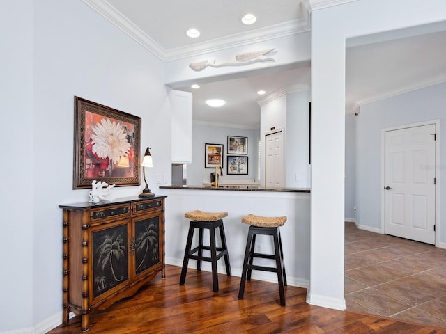 kitchen featuring ornamental molding, dark countertops, white cabinetry, and wood finished floors