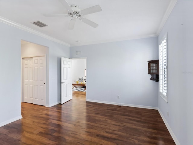 spare room with ornamental molding, visible vents, and wood finished floors