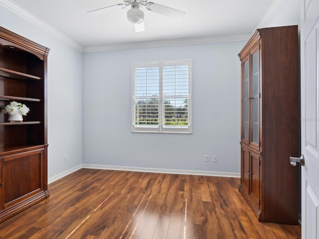 empty room featuring ornamental molding, ceiling fan, dark wood-type flooring, and baseboards