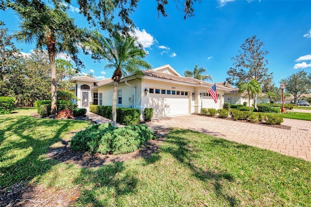 view of front of house with an attached garage, a tiled roof, decorative driveway, stucco siding, and a front lawn