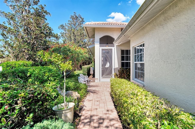 entrance to property featuring a tiled roof and stucco siding