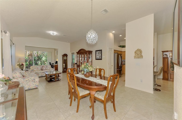 dining area with light tile patterned floors, visible vents, an inviting chandelier, vaulted ceiling, and a textured ceiling