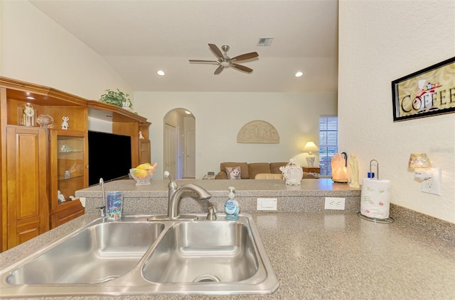 kitchen featuring visible vents, arched walkways, ceiling fan, vaulted ceiling, and a sink