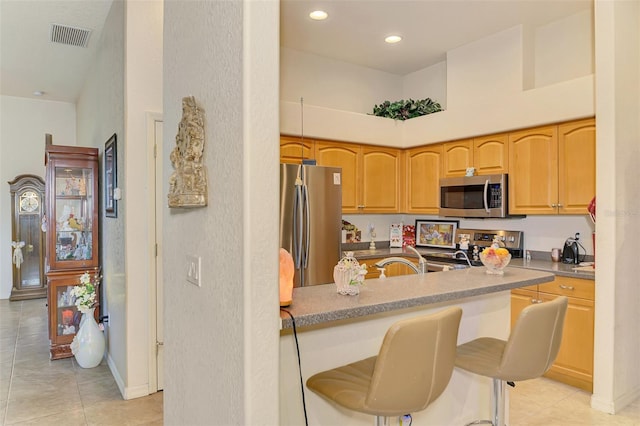 kitchen featuring recessed lighting, a towering ceiling, visible vents, a kitchen breakfast bar, and appliances with stainless steel finishes