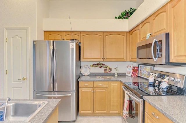 kitchen with light tile patterned floors, stainless steel appliances, light brown cabinetry, and a sink