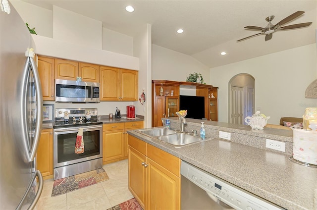 kitchen with arched walkways, recessed lighting, stainless steel appliances, a sink, and vaulted ceiling