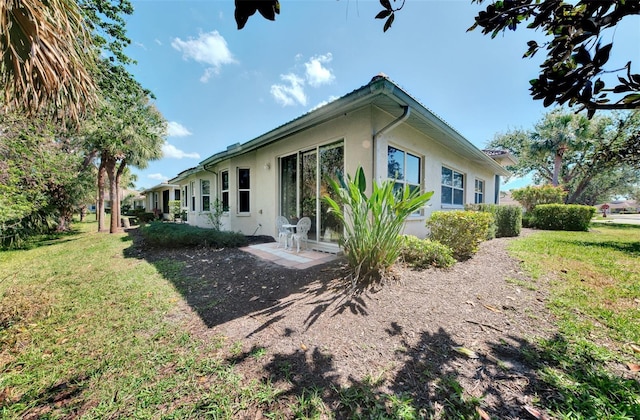 rear view of house with a lawn and stucco siding