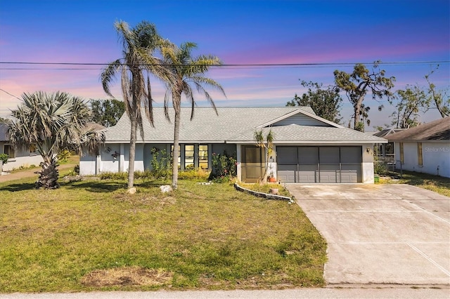 ranch-style home featuring driveway, a yard, an attached garage, and stucco siding