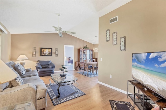 living area featuring visible vents, light wood-style floors, a ceiling fan, high vaulted ceiling, and baseboards