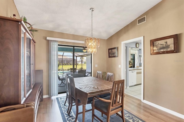 dining area with lofted ceiling, light wood-type flooring, visible vents, and baseboards