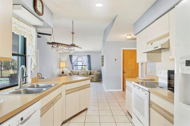 kitchen featuring light tile patterned floors, under cabinet range hood, white appliances, a sink, and light countertops