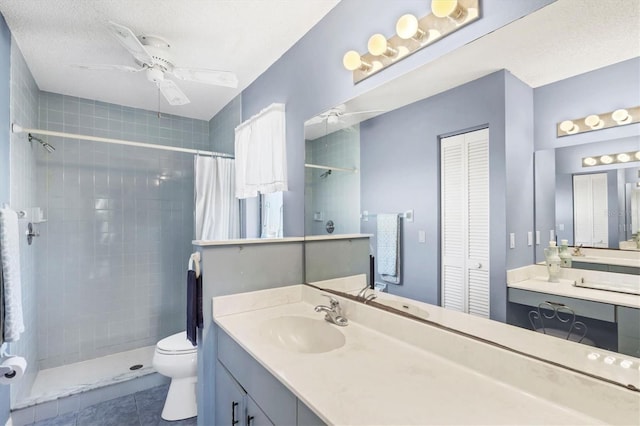 bathroom featuring a ceiling fan, toilet, a tile shower, vanity, and a closet