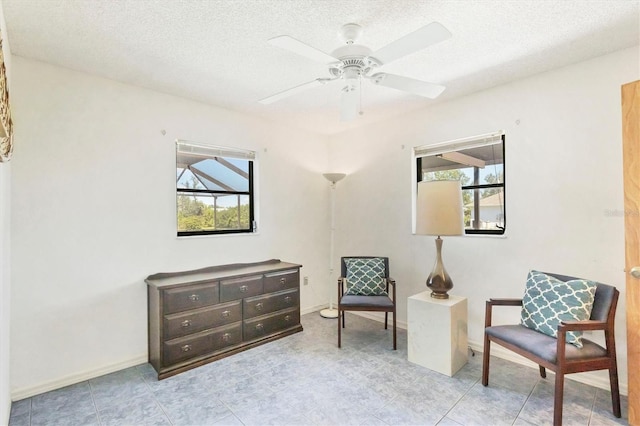 living area with a ceiling fan, a healthy amount of sunlight, and a textured ceiling